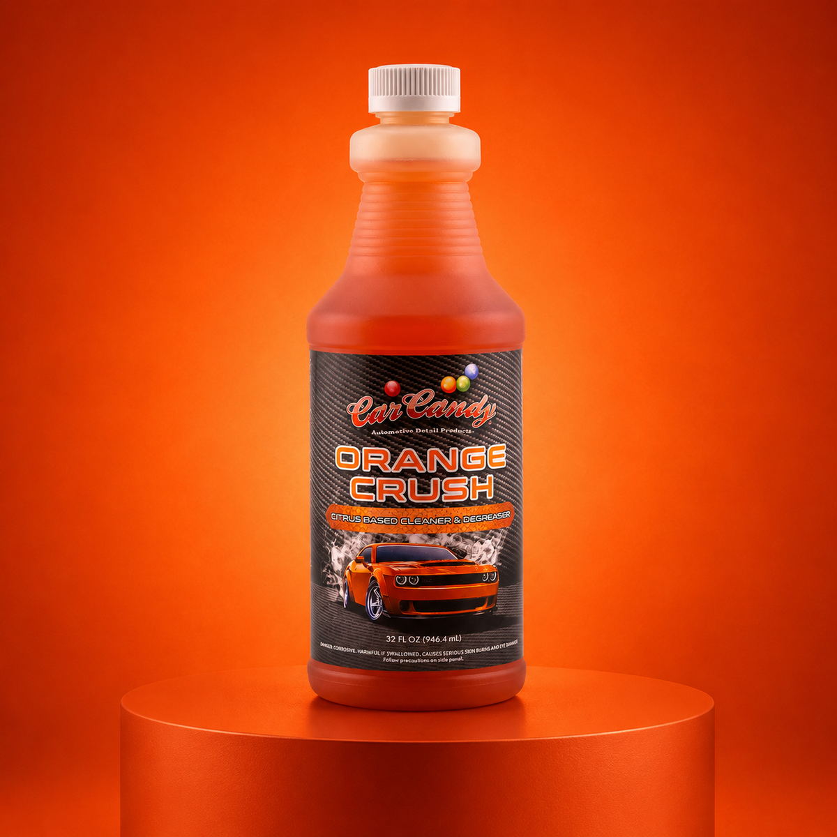 A bottle of Car Candy Orange Crush hand wash cleaner, filled with orange liquid, displayed on a matching orange cylindrical pedestal against a solid orange background.
